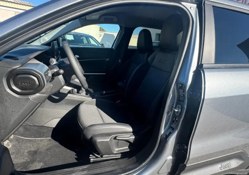 Intérieur côté conducteur du Jeep Avenger gris 2025, montrant siège avant avec logo Jeep et tableau de bord.