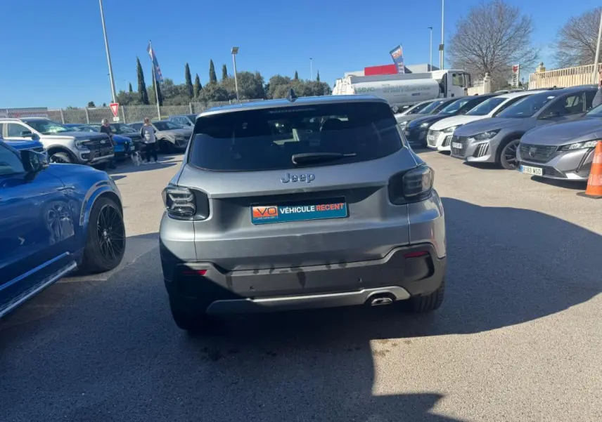 Vue arrière d'un Jeep Avenger gris 2025 avec feux arrière fumés et jantes alliage 18 pouces, stationné en extérieur.