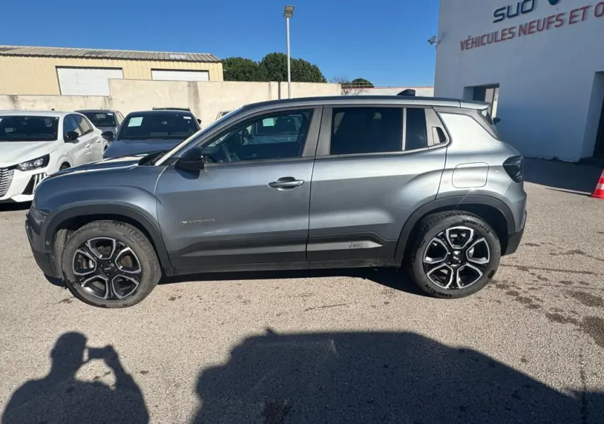 Profil côté gauche d’un Jeep Avenger gris 2025 avec jantes alliage noires et détails noirs sur les ailes.