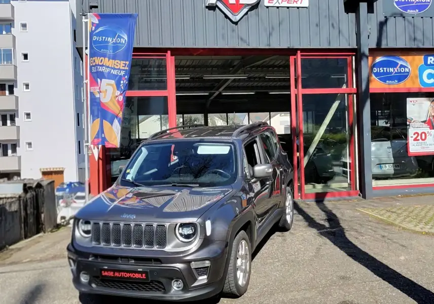 Jeep Renegade Granite Crystal métallisé en 3/4 avant droit, devant un garage avec enseigne AD Expert.