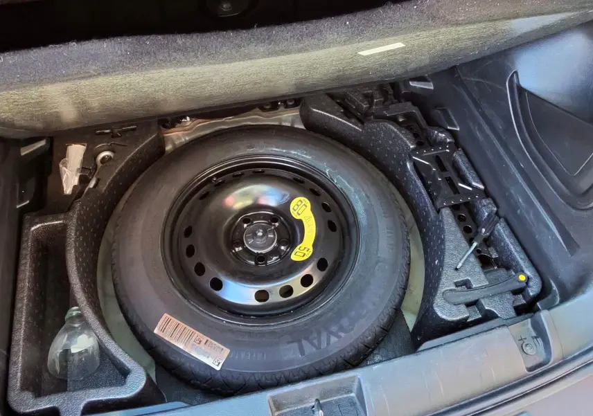 Vue du coffre ouvert d'un Jeep Renegade Granite Crystal, montrant la roue de secours et les outils de bord.