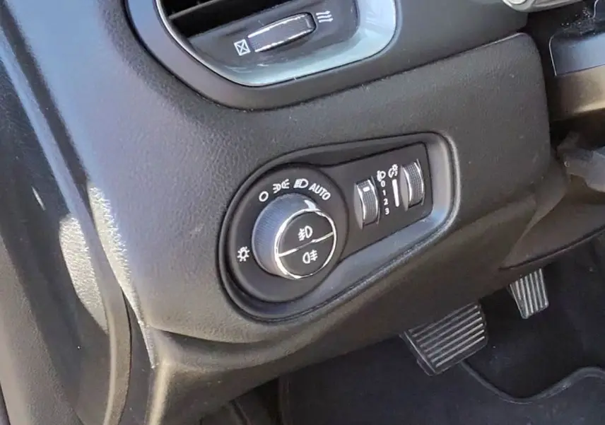 Gros plan sur le tableau de bord noir du Jeep Renegade 2020, montrant la commande des phares et les pédales.