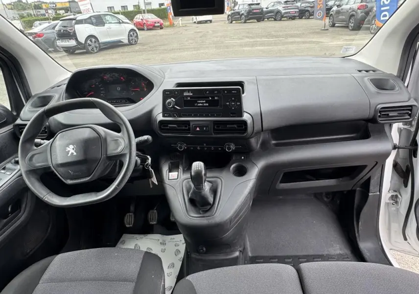 Vue intérieure avant du Peugeot Partner blanc 2020, montrant le volant, tableau de bord et levier de vitesses manuel.