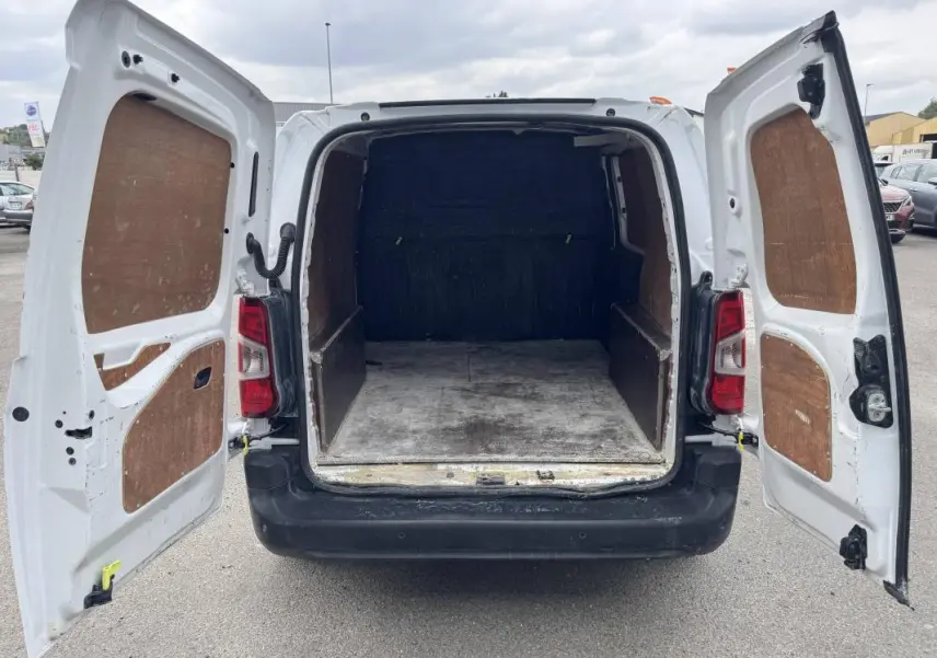 Vue arrière du Peugeot Partner blanc 2020 avec portes ouvertes dévoilant la zone de chargement vide et protégée par des panneaux en bois.