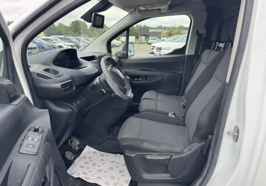 Vue intérieure côté conducteur du Peugeot Partner blanc 2020, montrant le tableau de bord et les sièges avant gris.