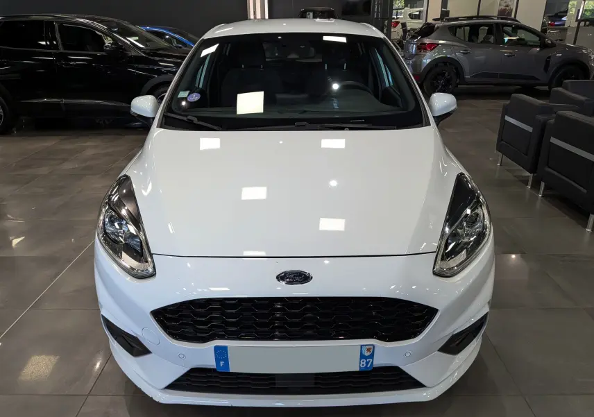 Vue frontale d'une Ford Fiesta blanche 2020 avec calandre noire et phares modernes dans un showroom.