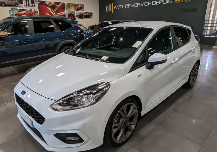 Ford Fiesta 1.0 EcoBoost blanche vue en 3/4 avant droit, avec jantes alliage et phares LED en showroom.