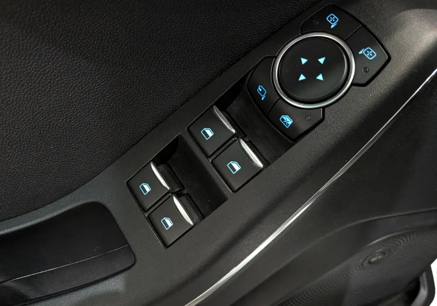 Gros plan sur les commandes de lève-vitres et rétroviseurs électriques côté conducteur d'une Ford Fiesta blanche 2020.