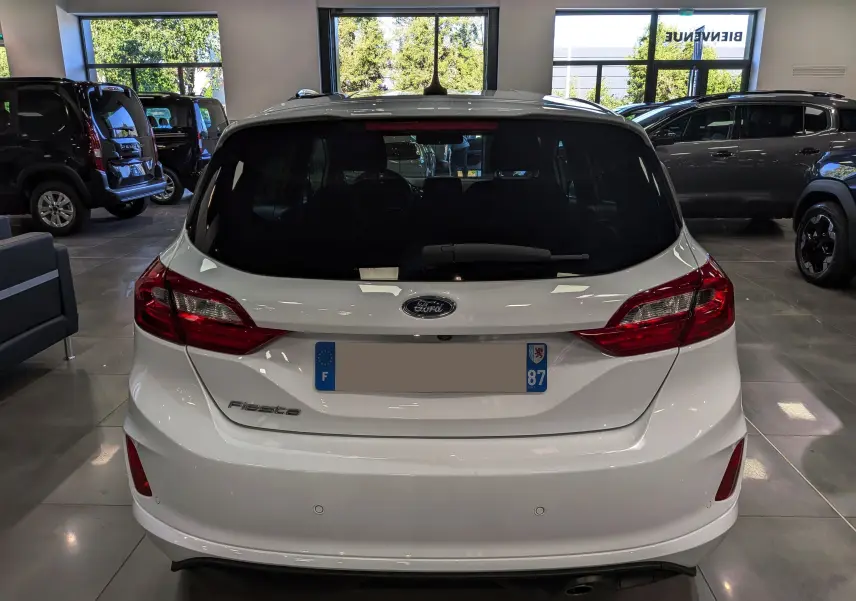 Vue arrière d'une Ford Fiesta blanche 2020 dans un showroom, mettant en valeur ses feux arrière et son hayon lisse.