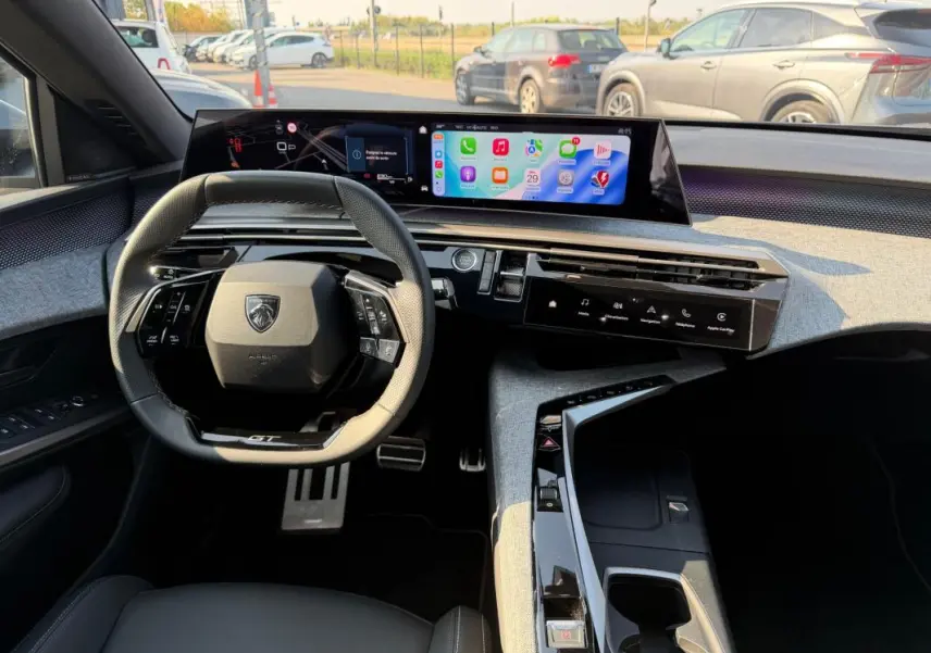 Vue intérieure du tableau de bord du Peugeot 3008 Hybrid GT 2025, avec volant compact et écran numérique panoramique.
