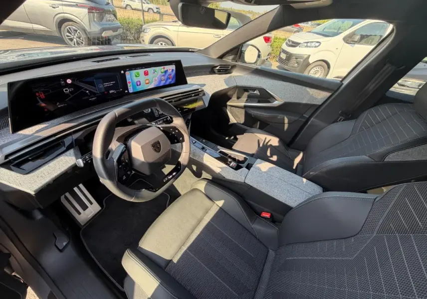 Intérieur du Peugeot 3008 Hybrid 2025 vu côté conducteur, avec tableau de bord numérique et sellerie gris foncé.