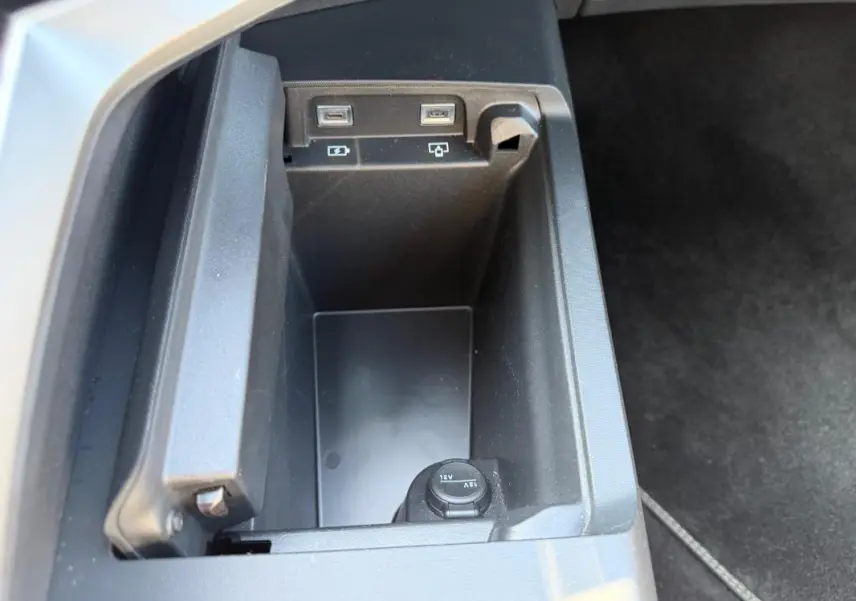 Gros plan sur le rangement intérieur avec prises USB et prise 12V du Peugeot 3008 Hybrid gris, version 2025.
