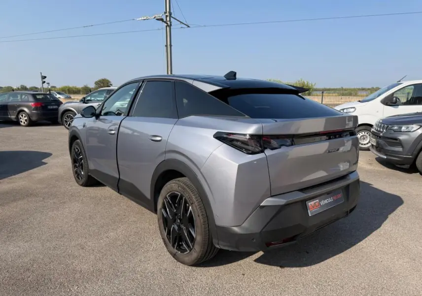 Vue 3/4 arrière droite d’un Peugeot 3008 Hybrid 145 gris avec jantes alliage noires de 19 pouces, sur parking extérieur.