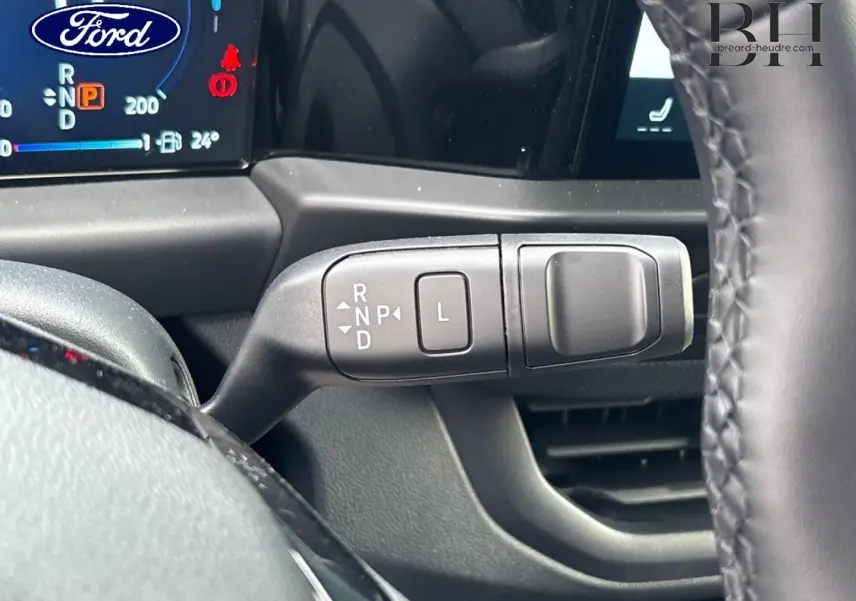 Gros plan sur la commande de boîte automatique à levier sur le côté droit du volant dans un Ford Transit Custom noir.