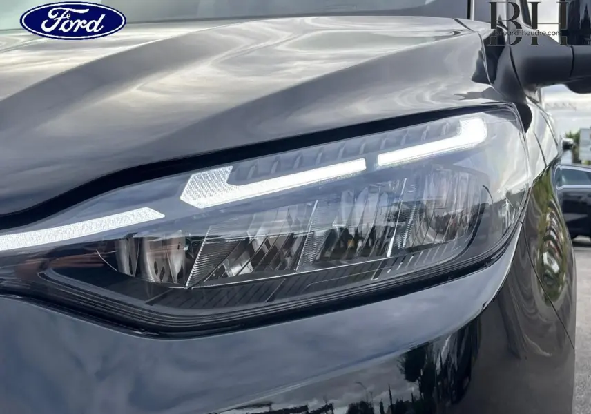 Gros plan sur le phare avant droit du Ford Transit Custom noir Agate Métallisée avec éclairage LED distinctif.