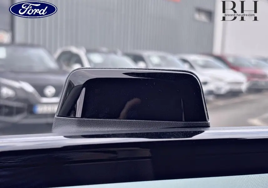 Gros plan sur l'antenne noire du Ford Transit Custom Fourgon 2026, couleur Noir Agate Métallisée, en extérieur flou.