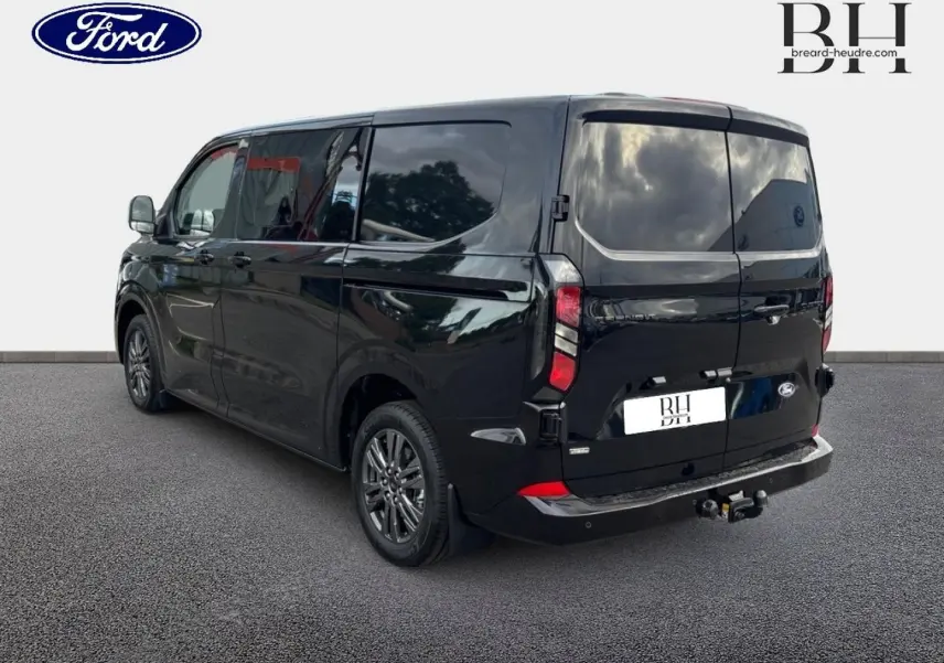Vue 3/4 arrière droite du Ford Transit Custom Fourgon noir Agate Métallisée avec crochet d'attelage et jantes alu gris carbone.