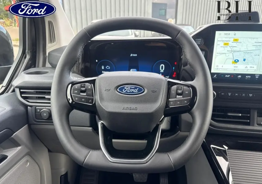 Vue frontale du volant et tableau de bord numérique du Ford Transit Custom Fourgon noir, avec écran tactile de navigation.