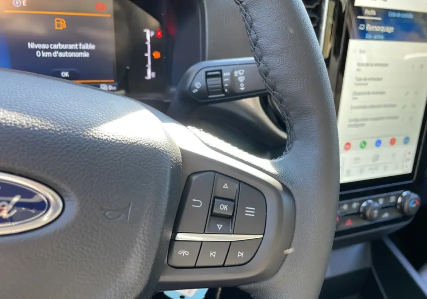 Gros plan sur le volant cuir multifonctions et l’écran tactile du Ford Ranger gris iconic, intérieur moderne et lumineux.