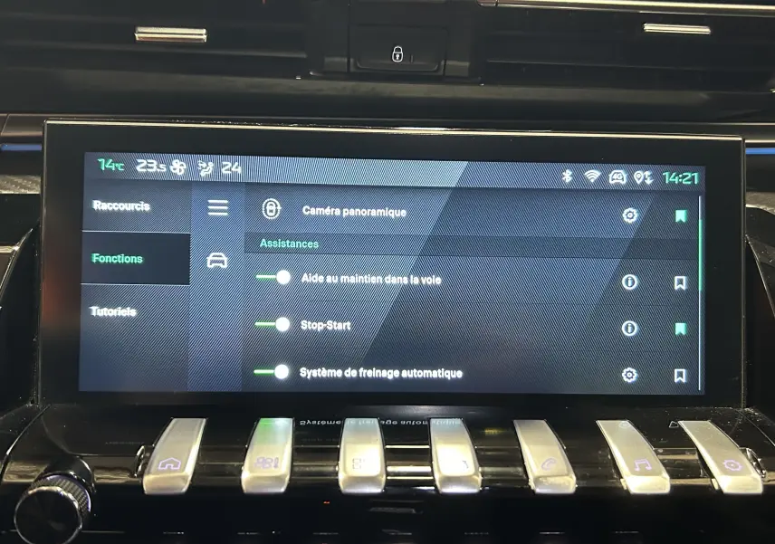 Écran tactile central de la Peugeot 508 SW 2024 montrant les assistances à la conduite, avec commandes piano en dessous.