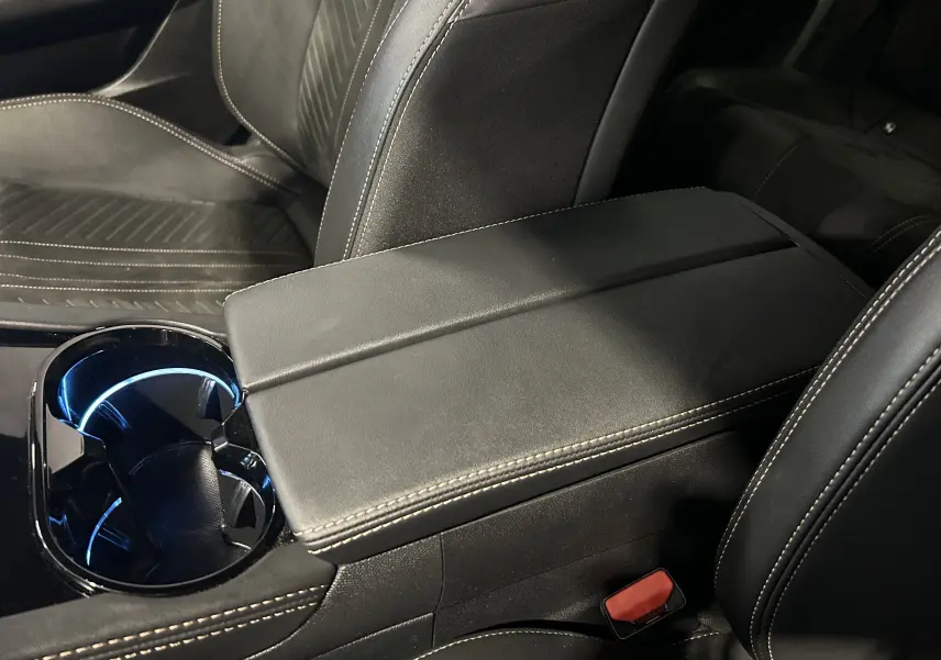 Gros plan sur l'accoudoir central et porte-gobelets éclairé de l'intérieur cuir noir de la Peugeot 508 SW 2024.