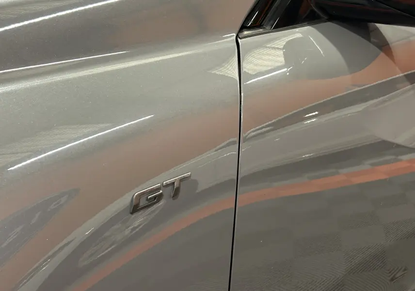 Détail du logo GT sur la porte côté gauche d'une Peugeot 508 SW gris Selenium brillante.