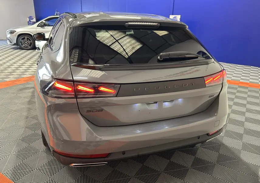 Vue 3/4 arrière d'une Peugeot 508 SW gris Selenium avec feux arrière allumés dans un showroom.