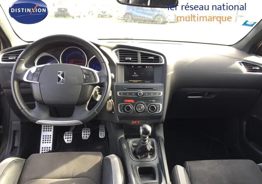 Vue intérieure avant du DS4 CROSSBACK gris platinium, mettant en valeur le volant multifonction et la boîte manuelle.