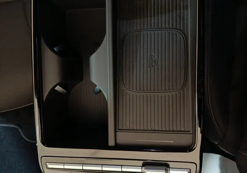 Vue plongeante sur la console centrale noire du Hyundai Tucson 1.6 Hybrid 2025 avec zone de recharge sans fil et commandes tactiles.