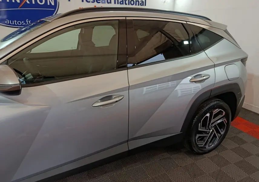 Vue latérale droite du Hyundai Tucson 1.6 Hybrid gris clair, soulignant les lignes anguleuses et les jantes distinctives.