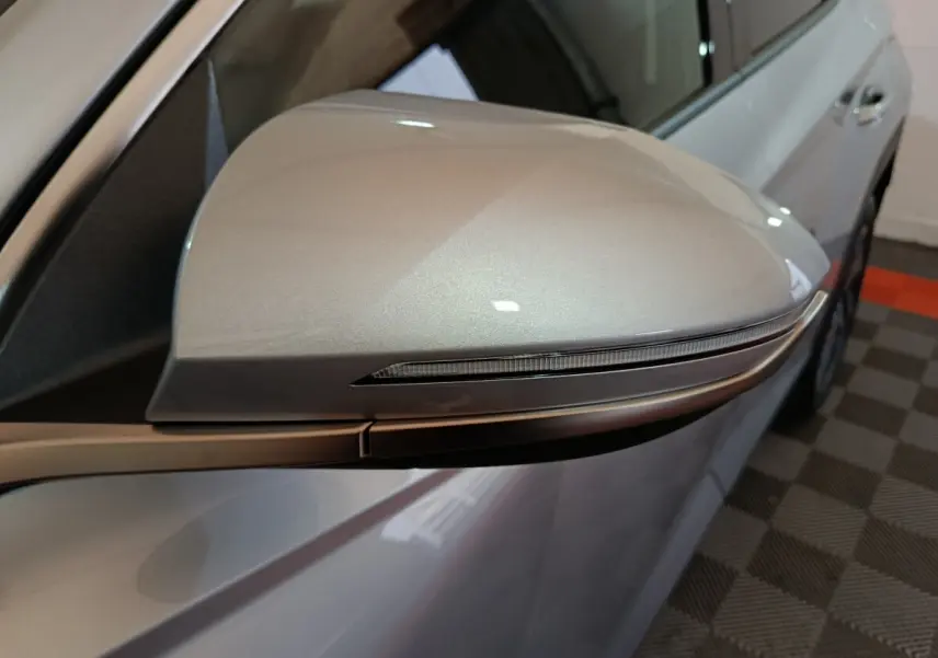 Gros plan sur le rétroviseur droit gris clair du Hyundai Tucson 2025 avec clignotant intégré, vue latérale partielle.