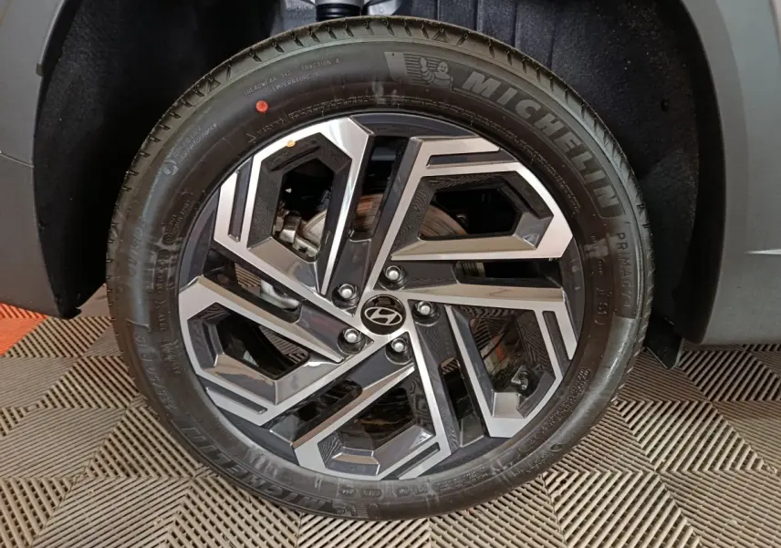 Gros plan sur la roue avant droite du Hyundai Tucson gris clair 2025 avec jante alliage au design géométrique.