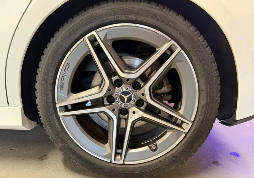 Gros plan sur la jante AMG argentée d’une Mercedes Classe A 220D blanche, vue côté gauche.