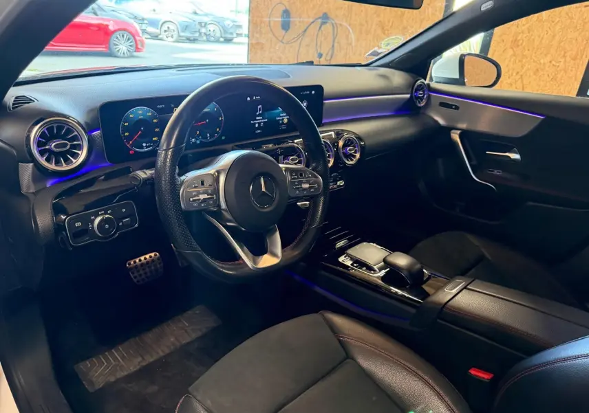 Vue intérieure côté conducteur de la Mercedes Classe A 220D AMG Line 2019 avec tableau de bord numérique et éclairage d'ambiance violet.