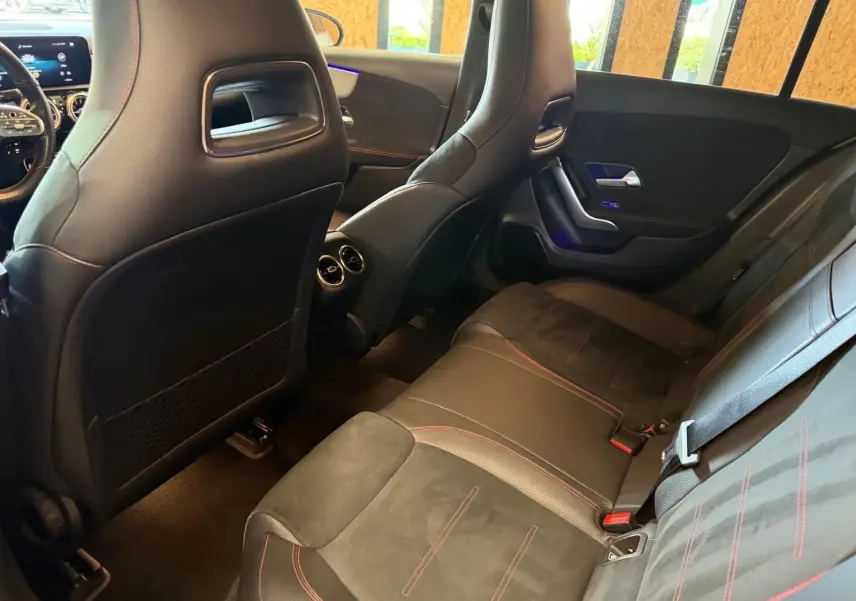 Vue intérieure arrière droite de la Mercedes Classe A 220D AMG Line 2019 avec sièges noirs et surpiqûres rouges.
