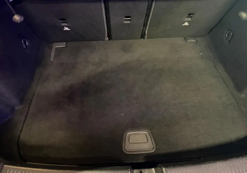 Vue intérieure du coffre noir de la Mercedes Classe A 220D AMG Line blanc, espace de chargement propre et vide.