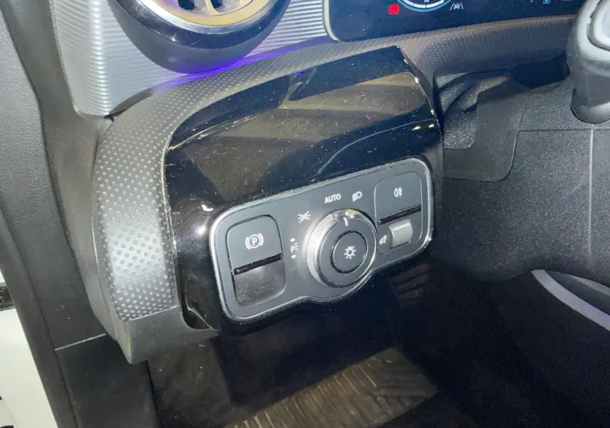 Gros plan sur le tableau de bord côté gauche de la Mercedes Classe A 220D AMG Line 2019 avec commandes d’éclairage et frein à main électrique.