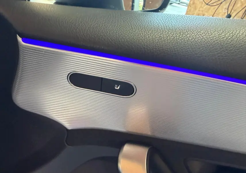 Détail de la commande de siège chauffant sur la porte côté gauche d’une Mercedes Classe A 220D AMG Line blanche.