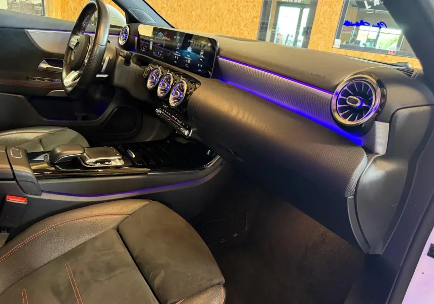 Vue intérieure côté passager de la Mercedes Classe A 220D AMG Line 2019 avec éclairage d'ambiance violet et sellerie noire.