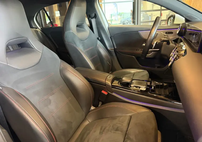 Vue intérieure côté conducteur de la Mercedes Classe A 220D AMG Line 2019 avec sièges sport noirs et surpiqûres rouges.