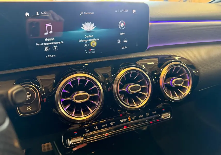 Vue rapprochée du tableau de bord noir de la Mercedes Classe A 220D AMG Line 2019 avec aérateurs ronds et écran digital.