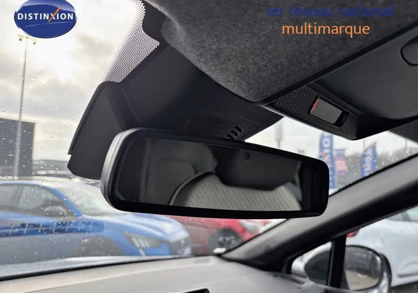 Vue intérieure du rétroviseur central d’un Renault Captur gris rafale métal avec toit noir, sous pluie légère en concession.