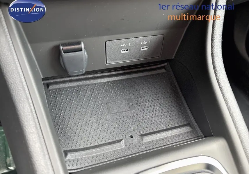 Gros plan sur la console centrale du Renault Captur II hybride 2025, montrant les ports USB-C et un espace de rangement noir texturé.