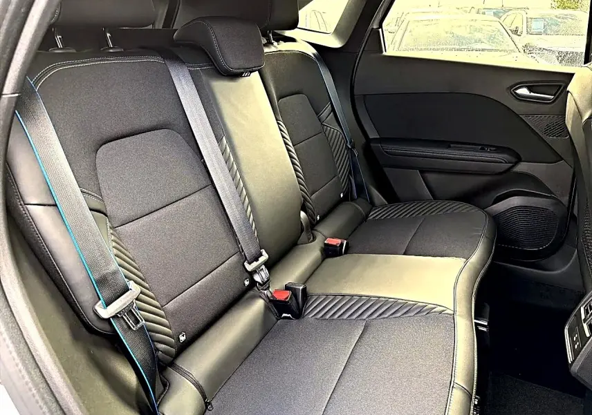 Vue intérieure de la banquette arrière noire avec surpiqûres bleues du Renault Symbioz gris rafale, version hybride 2026.