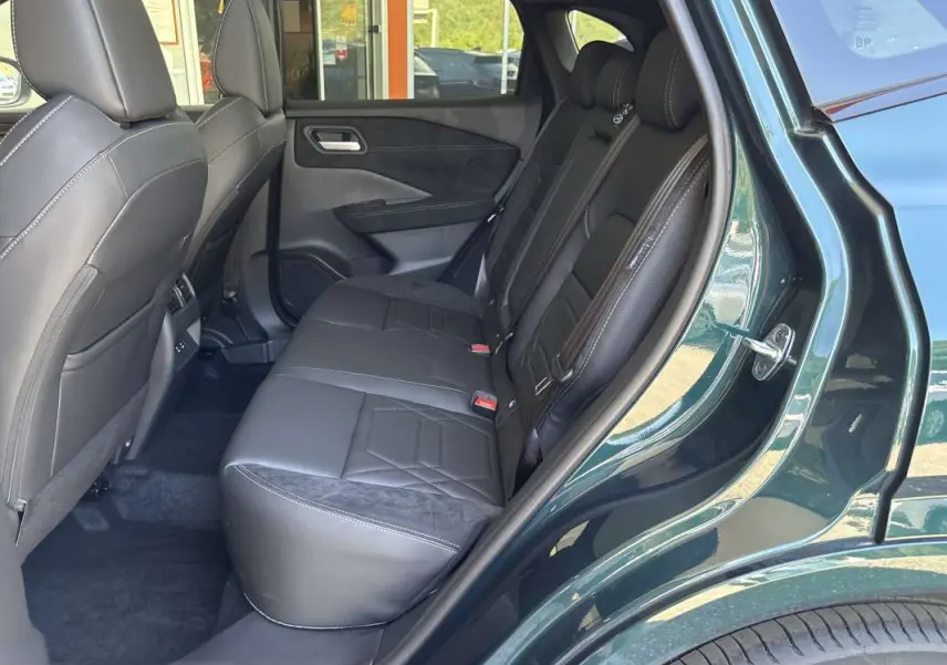 Vue côté droit de la banquette arrière en cuir alcantara noir du Nissan Qashqai E-POWER 2026 vert cayuga avec porte ouverte.