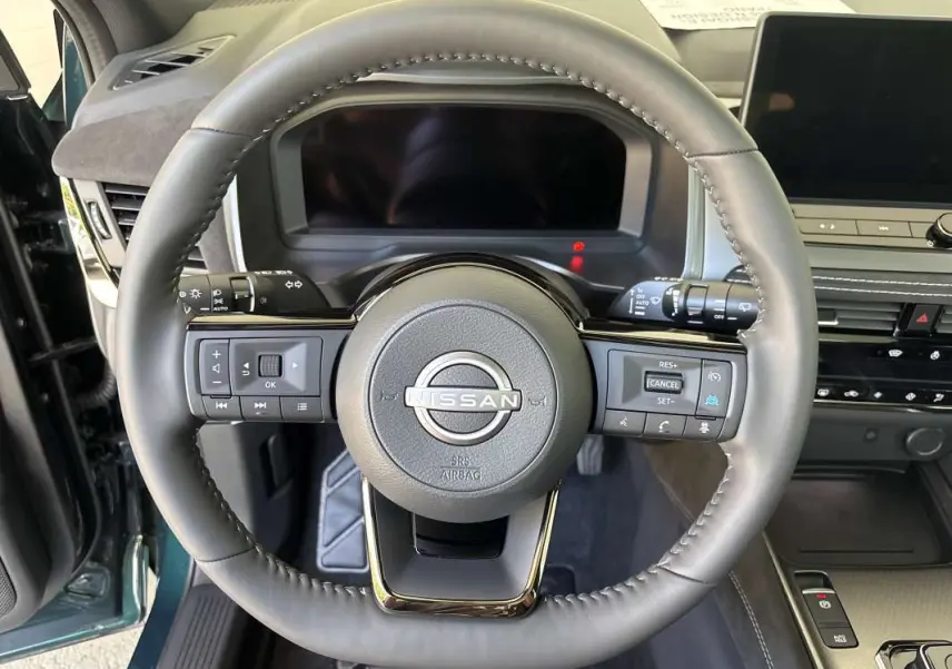 Vue rapprochée du volant cuir multifonctions du Nissan Qashqai E-POWER 2026, intérieur avec tableau de bord moderne.