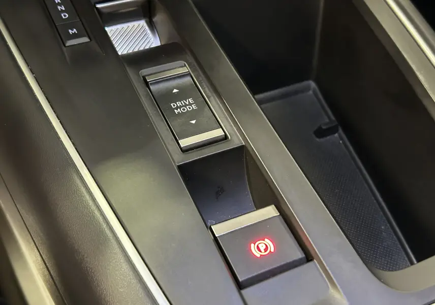 Gros plan sur la console centrale noire du Citroën C5 Aircross 2024 avec bouton frein à main électronique et sélection drive mode.