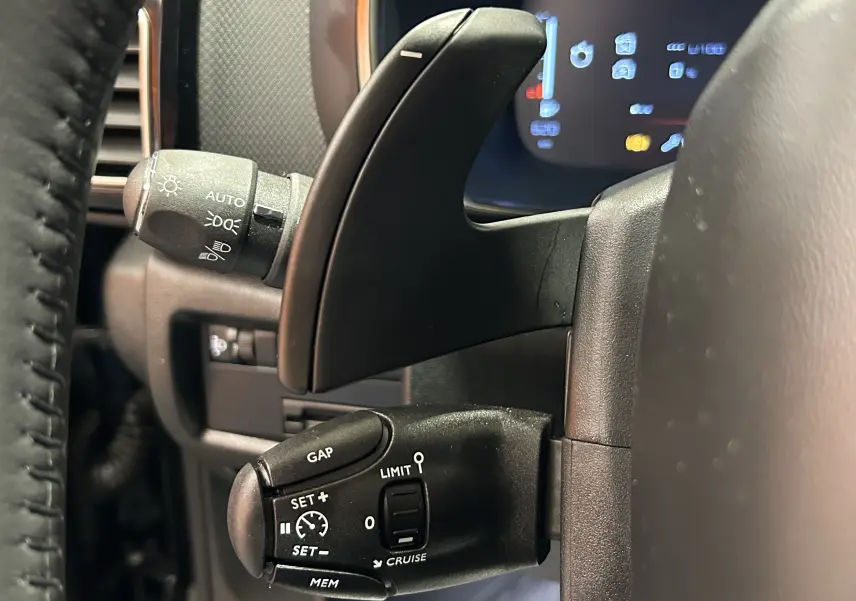 Détail du commodo noir à gauche du volant d'une Citroën C5 Aircross 2024, avec régulateur adaptatif visible.