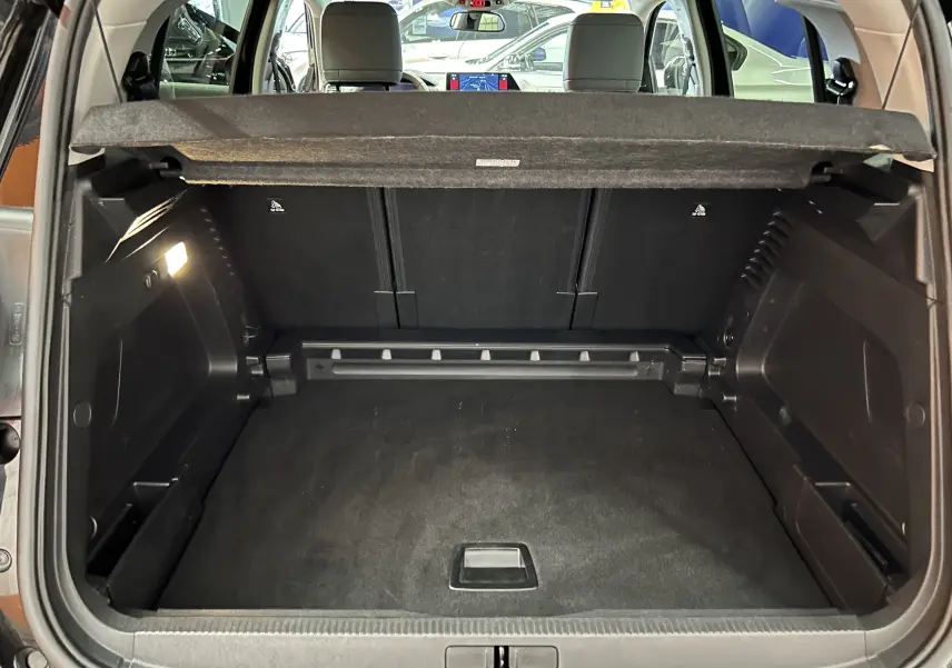 Coffre ouvert vu de l'arrière du Citroën C5 Aircross noir Perla Nera avec banquette arrière et tablette cache-bagages visibles.