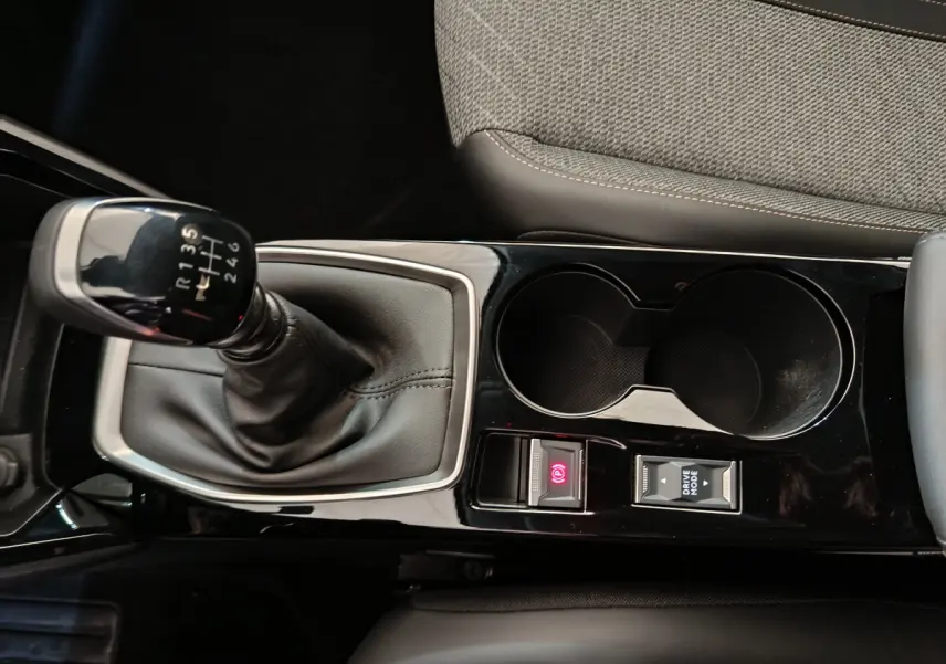 Vue rapprochée de la console centrale noire avec levier de vitesses manuel et porte-gobelets du Peugeot 208 gris clair